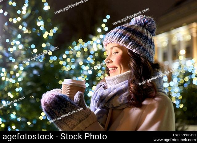 happy woman drinking coffee over christmas lights
