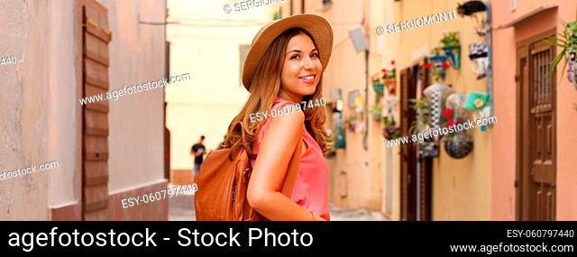 Tourism in Sardinia. Panoramic banner view of traveler girl walking in picturesque narrow alley of Alghero, Italy. Young female backpacker visiting Europe