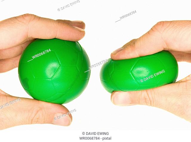 A stock photograph of a mans hand squeezing a green stress ball