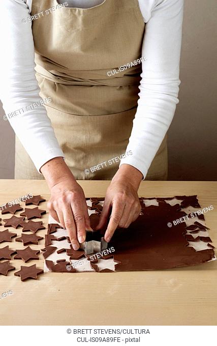 Woman using star shaped pastry cutter to cut chocolate