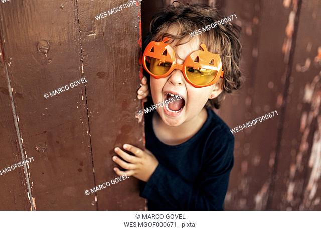 Portrait of little screaming girl wearing halloween glasses shaped like pumpkins