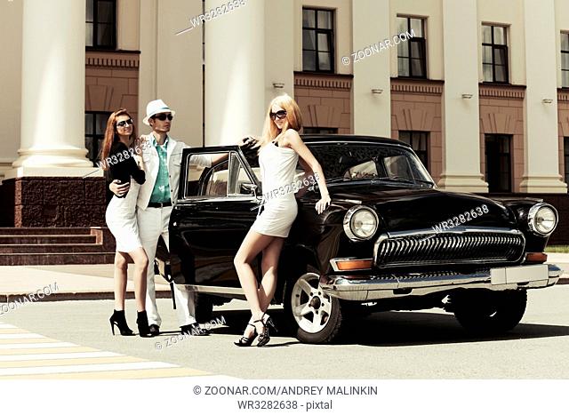 Young fashionable people at the retro car