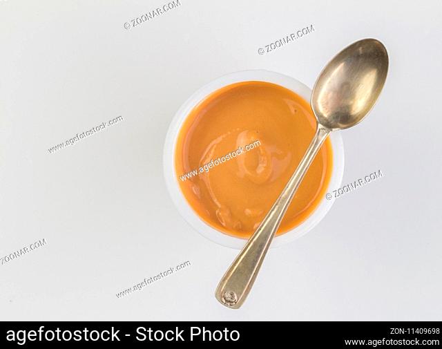 Yogurt background top view shot of caramel flavoured yoghurt in plastic cup with small silver spoon isolated on white background - close up image with space for...