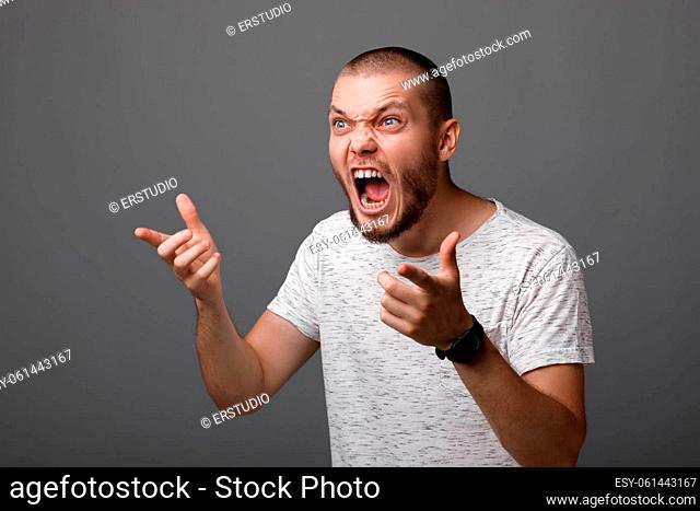 portrait of angry screaming young man on gray background