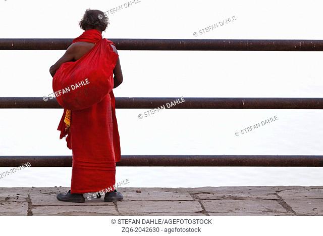 Man in red Frock looking onto the River Ganges in Varanasi, India