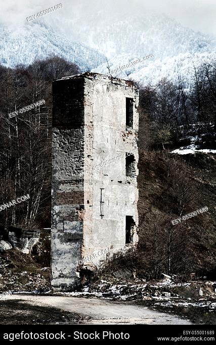 The ruins of the tower on the background of winter forest mountains