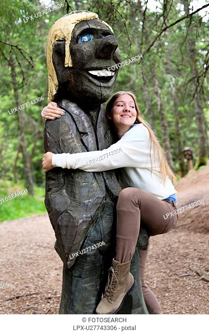 Woman hugging a Troll sculpture in a park, Bergen, Norway