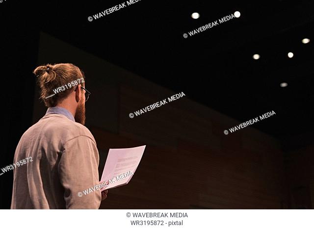 Male actor reading script on stage