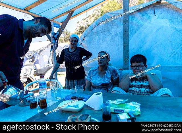 PRODUCTION - 19 July 2023, Turkey, Antakya: Ayfer Orukcu (2nd from right) lives with her son (r), her mother Nuriye and her brother Aziz (l) in a tent near...