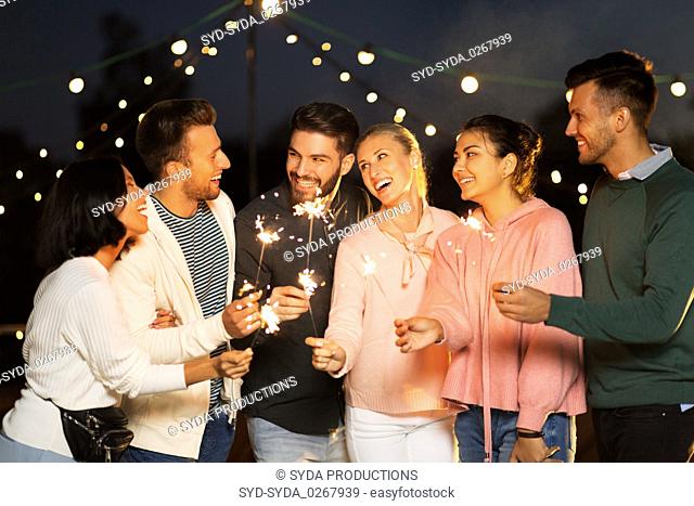 happy friends with sparklers at rooftop party