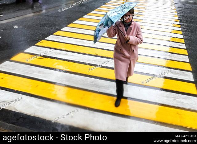RUSSIA, MOSCOW - NOVEMBER 2, 2023: A woman holding an umbrella crosses a street in the rain in late autumn. Sergei Bobylev/TASS