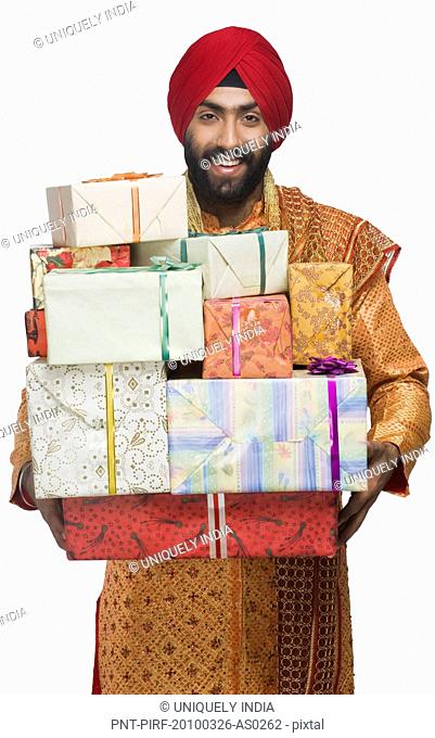 Portrait of a Sikh man holding stack of presents