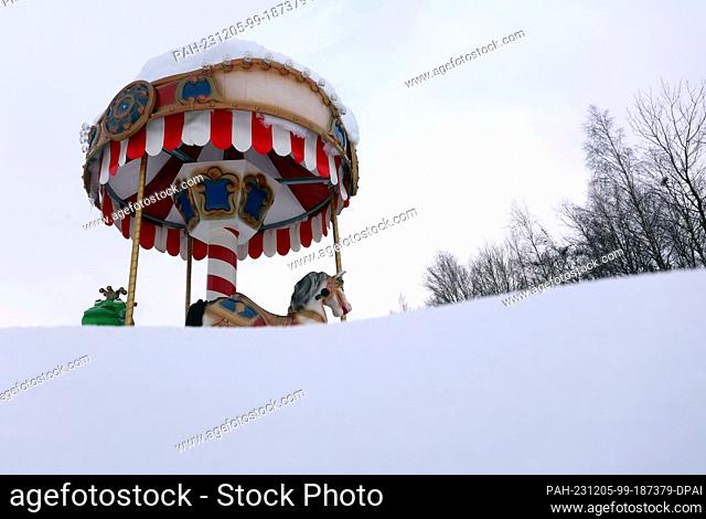 05 December 2023, Bavaria, Aitrang: A children's carousel stands in the snow near a restaurant on Lake Elbe. Photo: Karl-Josef Hildenbrand/dpa