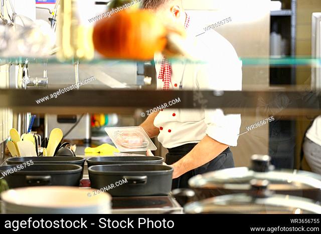 Chef is stirring and cooking rice in kitchen.. Chef cooking with cooking utensils, preparing for guests