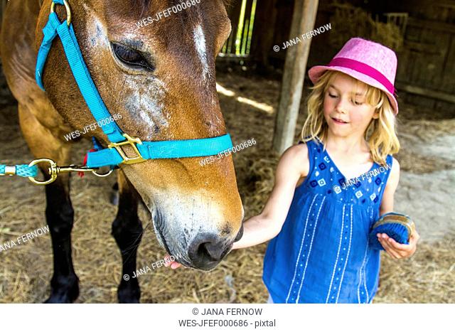 Greece, Corfu, Agios Georgios, little girl stroking horse
