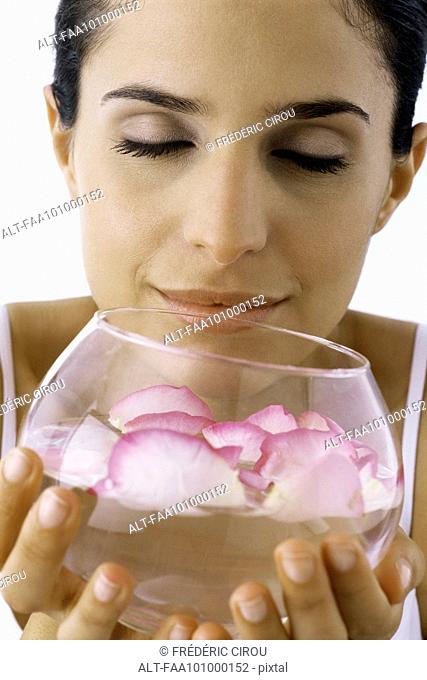 Woman smelling petals floating in bowel of water