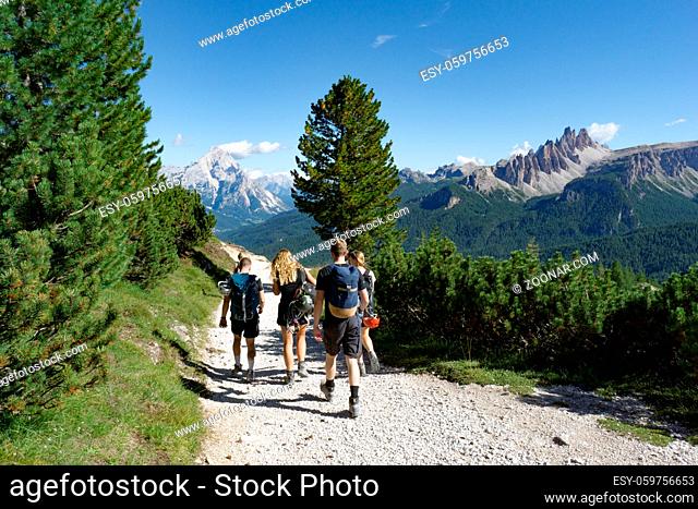 climbers walking down a road in a Dolomite mountain landscape after a hard climb with a great panorama view behind them of the Alta Badia mountains