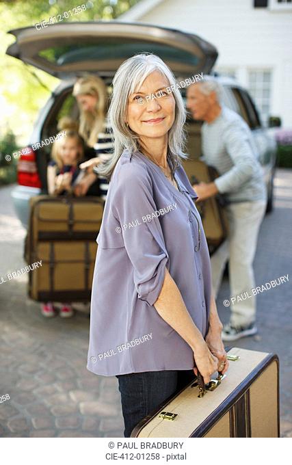 Woman carrying suitcase to trunk