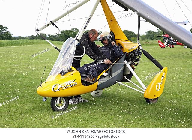 microlight aircraft with the instructor fastening the safety belt of a pupil about to have a flying lesson