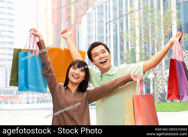 Portrait of young couple posing with shopping bags in hands, Beijing, China