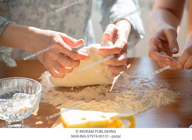Women cooking pizza at home. Two unrecognizable women kneading dough