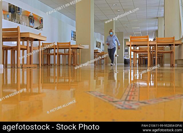 11 June 2021, Saxony-Anhalt, Magdeburg: A staff member walks through the dining room at Magdeburg Youth Hostel. Many school trips have been cancelled because of...