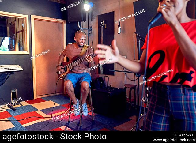 Musicians singing and playing guitar in recording studio