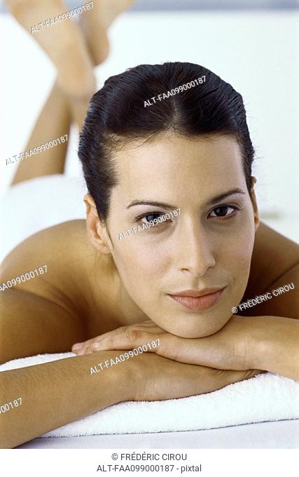 Woman lying on stomach with head resting on arms, portrait