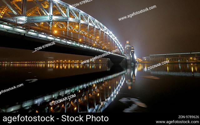 Illuminated Peter the Great Bridge across Neva River in night Saint Petersburg, Russia