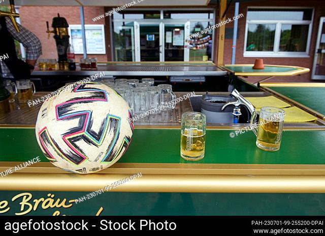 PRODUCTION - 01 July 2023, Lower Saxony, Deblinghausen: A soccer ball lies on the counter of the drinks stand next to two beers before the start of the match...