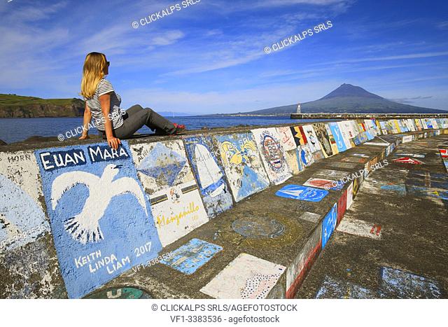 Woman sitting at the port of Horta observes Pico Island, Marina da Horta, Cais de Santa Cruz, Faial, Azores, Portugal, Western Europe