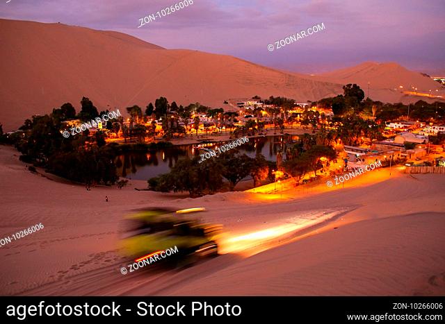 Oasis of Huacachina at night with dune buggy blurred motion, Ica region, Peru