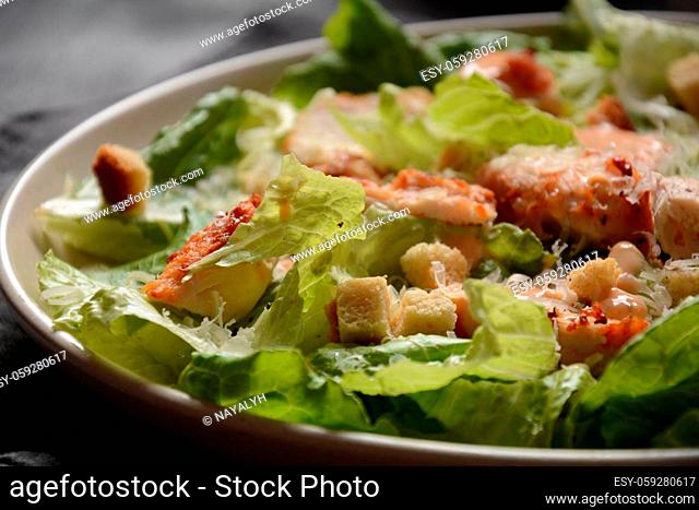 Caesar Salad with grilled chicken, Cheese and Croutons with lettuce, on plate. Grilled chicken breasts and fresh vegetables in plate