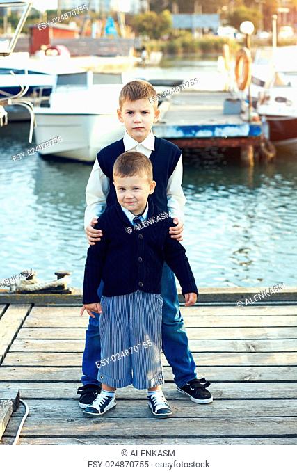 Fashion kid boys wearing navy clothes in marine style posing in the sea port