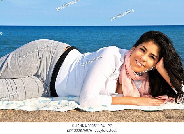 Portrait of beautiful smiling native american girl laying at beach