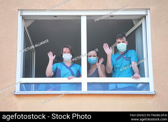22 April 2020, Saxony, Dresden: Nurses of the Elbflorenz senior citizens' home in Dresden wave from a window to the guests of a donation handover to the home