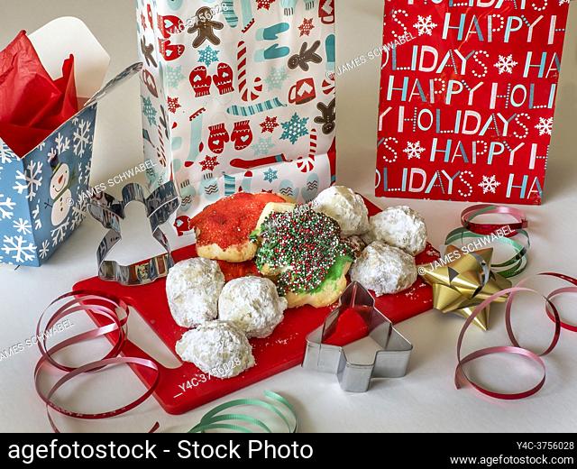 Assorted Christmas cookies on a red cutting board with holiday packages and ribbon