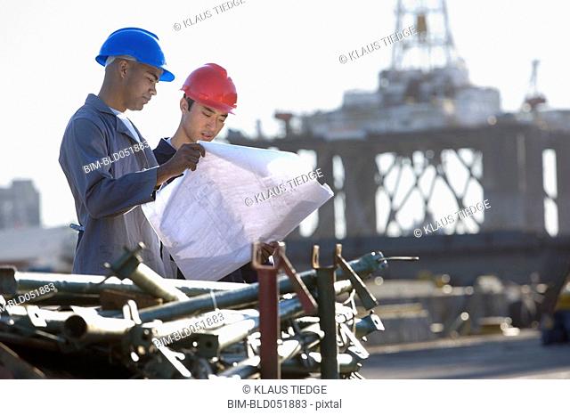 Multi-ethnic male construction workers looking at blueprints