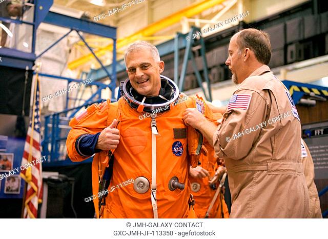 Astronaut Dave Wolf, STS-127 mission specialist, gets help in the donning of a training version of his shuttle launch and entry suit in preparation for a...