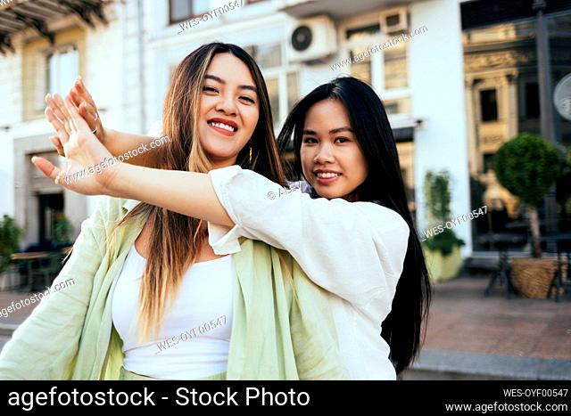 Smiling woman hugging female friend at city street