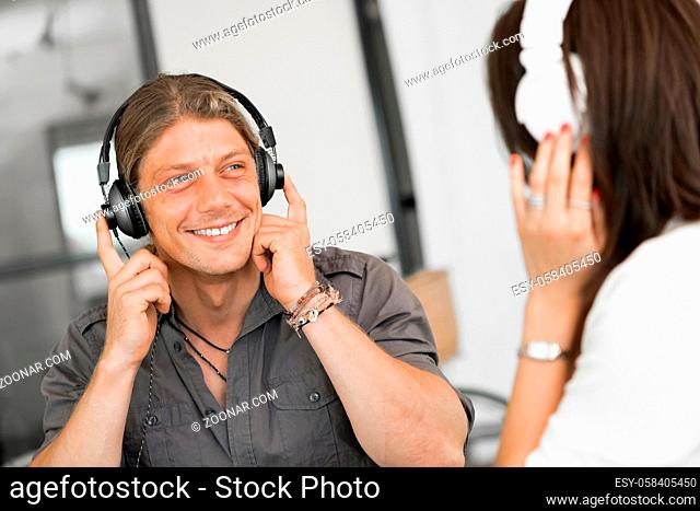 Portrait of young man and woman in office wearing headphones