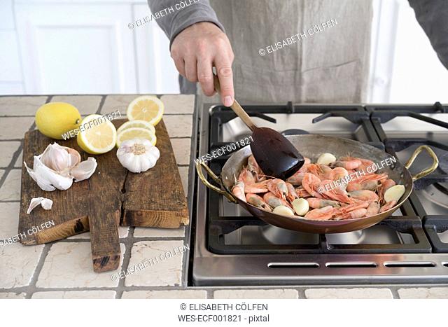 Man frying shrimps in pan
