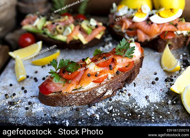 Salted salmon open sandwich with tomatoes, cream cheese, cucumber, parsley and pepper. Healthy delicious seafood