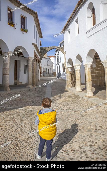 Impressive square of Garrovillas de Alconetar, Caceres, Extremadura, Spain. Child boy observing one of the square gates