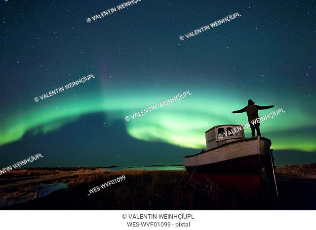 Norway, Lofoten Islands, Eggum, man admiring northern lights, standing on fishing boat