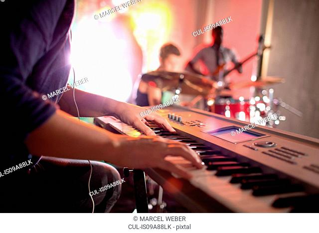 Woman playing keyboard, band in background