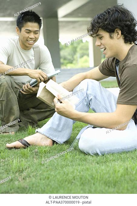 Two college students sitting in grass, studying