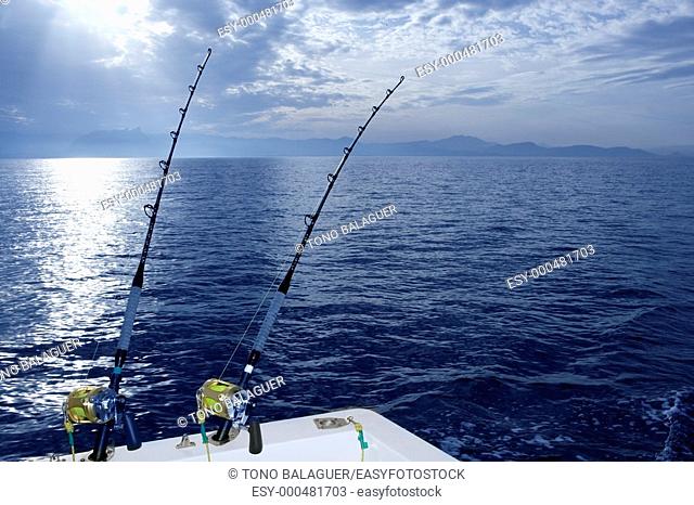 Fishing boat trolling with two rods and reels on blue ocean
