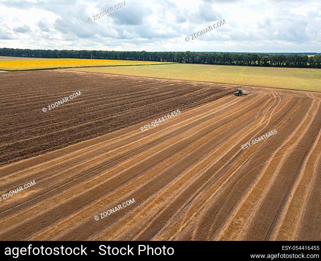 Panoramic view of plowing the ground after harvesting on the field in the autumn time. Aerial view from the drone of the field after harvest