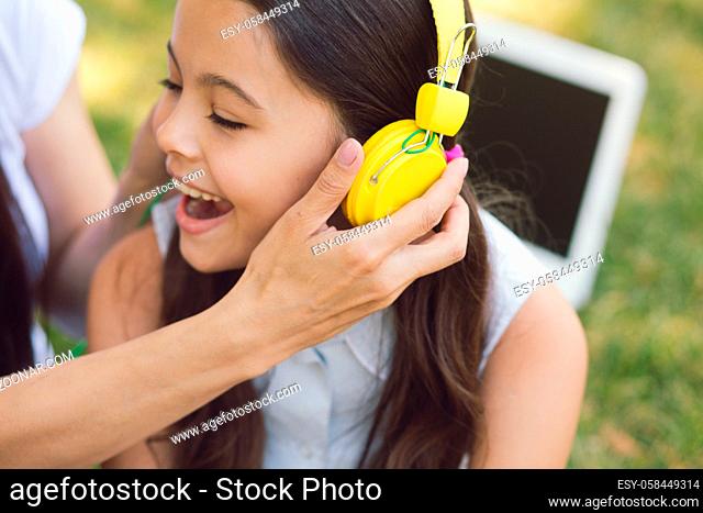 Girl Listens To Music In Yellow Headphones. Being In Park With Teacher And Schollmate